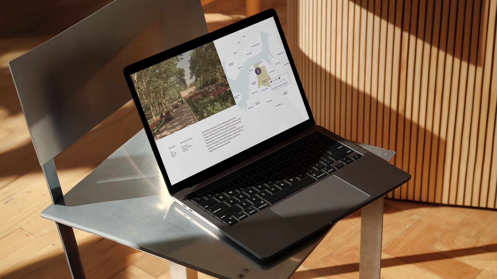 A laptop on a gray chair displays a map and park image on its screen, with sunlight casting shadows.