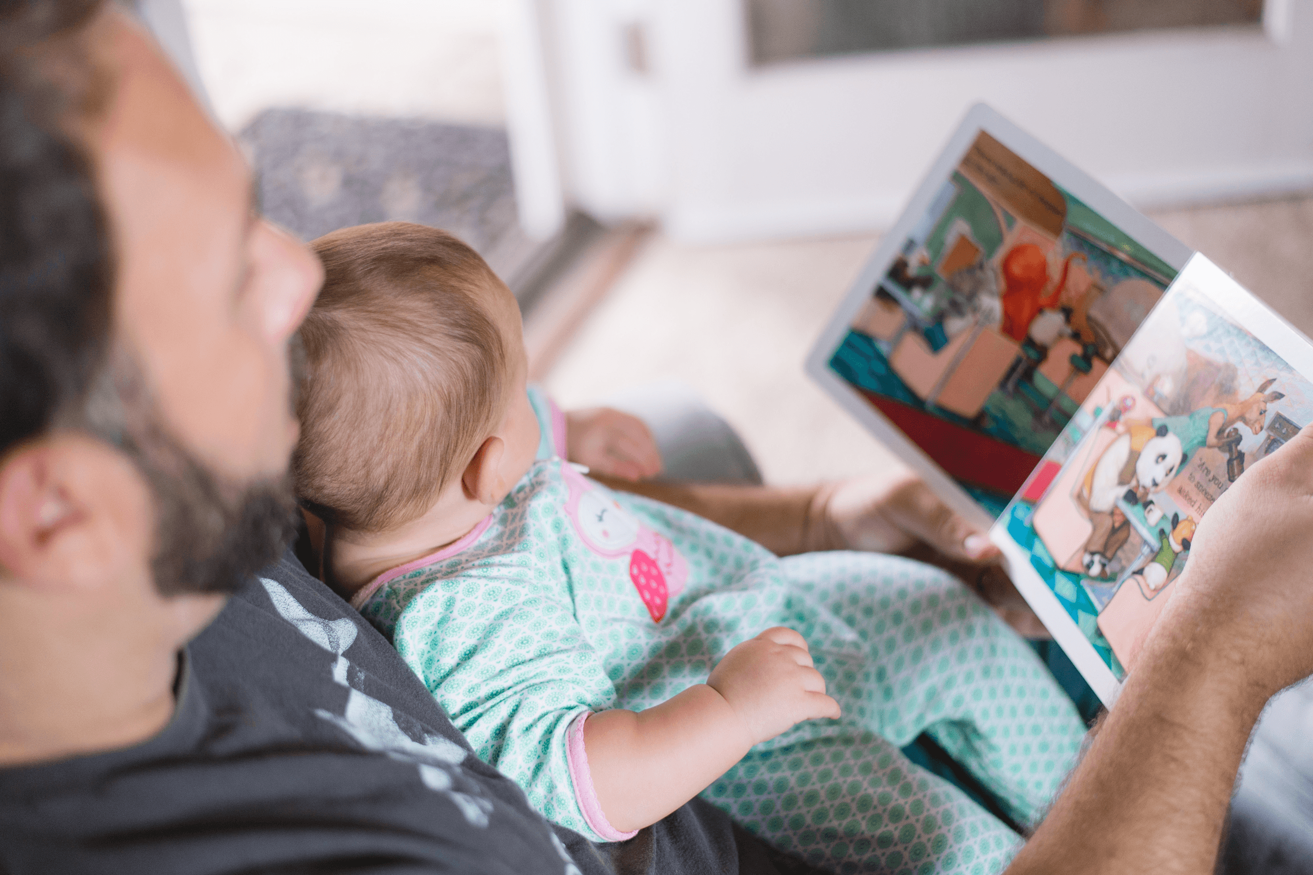 Ein Elternteil liest einem Baby aus einem Bilderbuch vor.