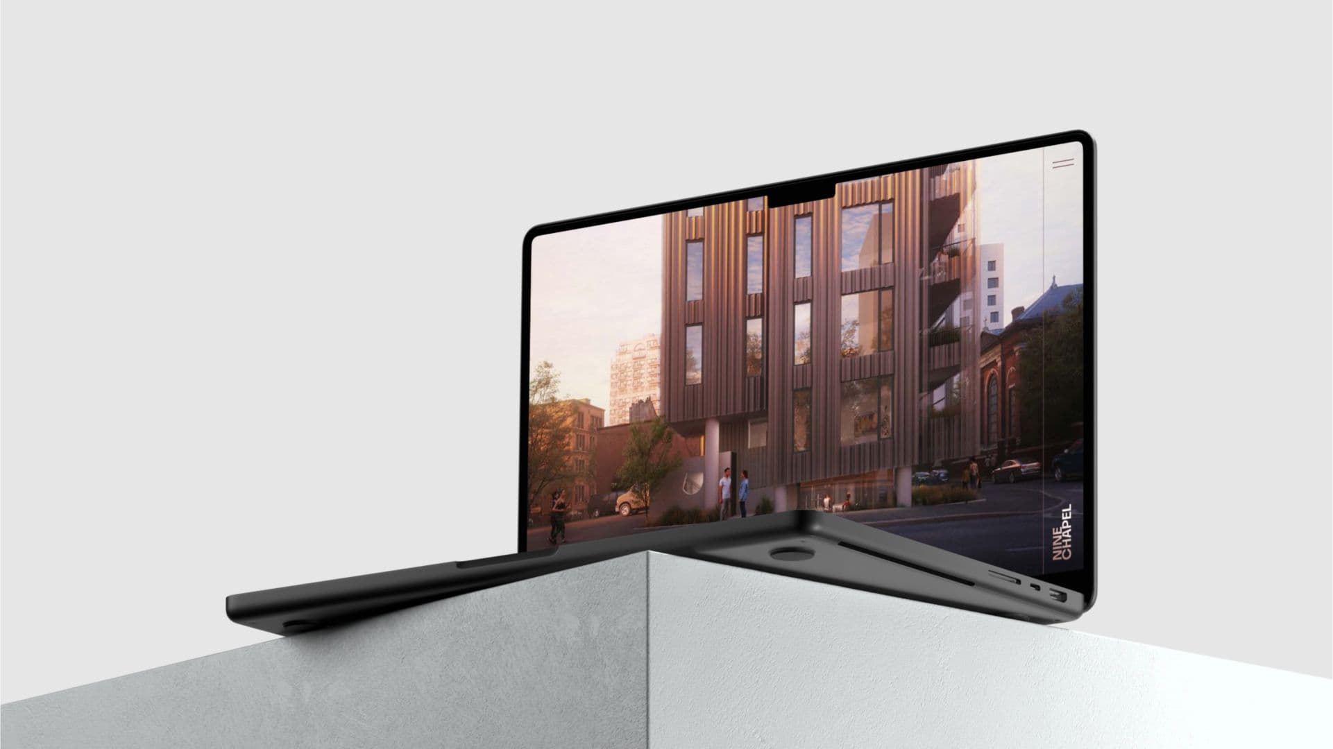 A dark grey laptop displaying an architectural rendering of a modern building, angled on a concrete block.