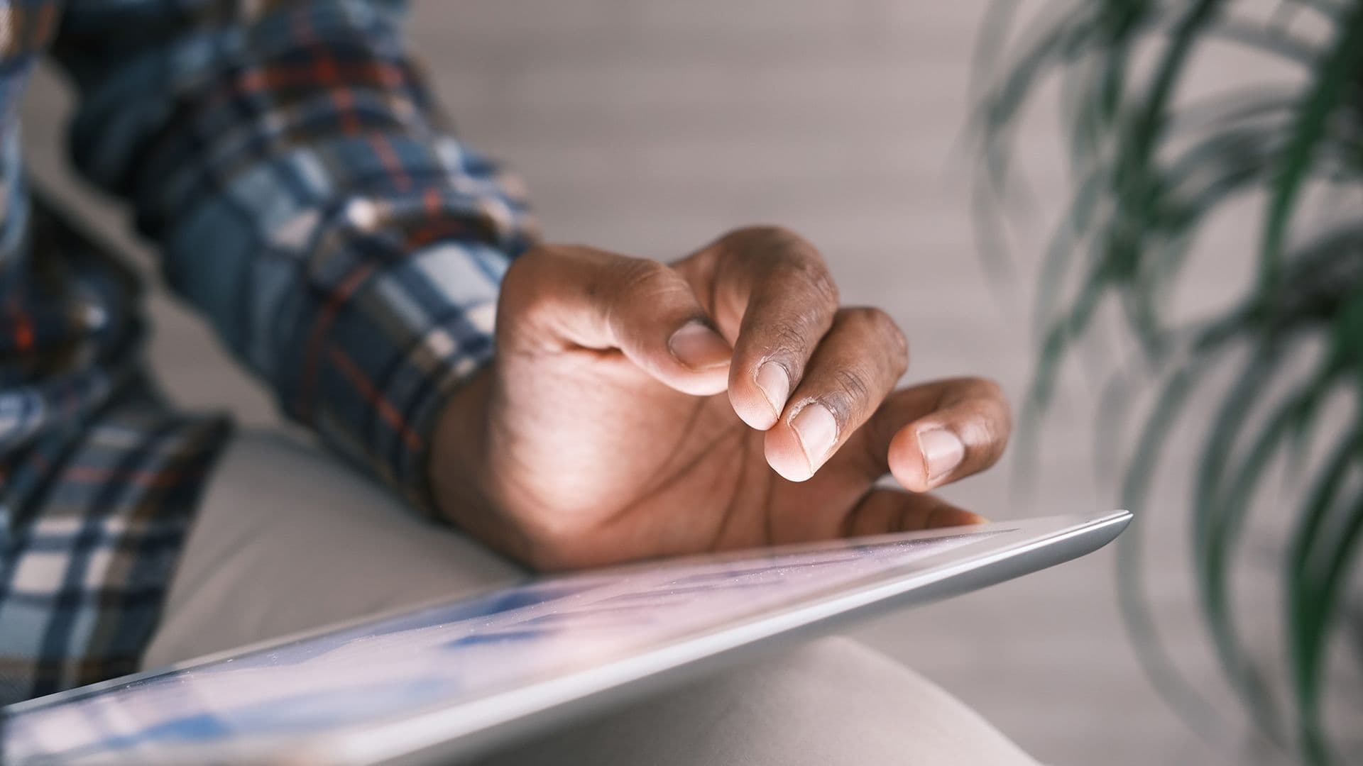 a man is using a tablet computer while sitting on a couch .
